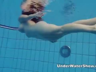 Redheaded femme fatale swimming nude in the pool
